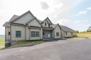 A modern two-story house with a stone facade, a large driveway, and a well-maintained lawn. - Lazy Creek - Deep Creek Lake - Indoor Lazy River , Boat Dock rental available May-Sept. 2026 (Deep Creek)