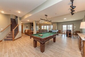 A spacious living area with a pool table, a staircase, and a kitchen area. - Lazy Creek - Deep Creek Lake - Indoor Lazy River , Boat Dock rental available May-Sept. 2026 (Deep Creek)