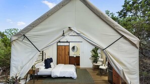 A tented accommodation with a bed, a small table, and a chair. - Cherry Cove Glamping W/ Hot tub AND Cowboy Pool! (Fredericksburg)