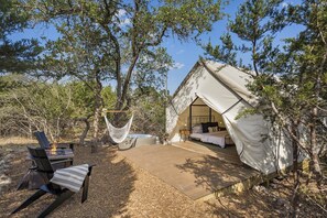 A tented accommodation with a bed, a hammock, and a fire pit.