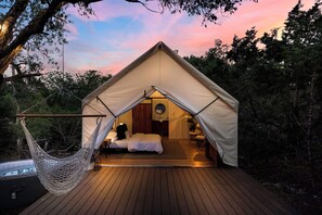 A cozy tented accommodation with a hammock, a bed, and a small bathroom. - Cherry Cove Glamping W/ Hot tub AND Cowboy Pool! (Fredericksburg)