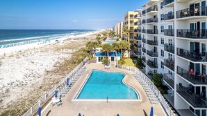 Un complexe hôtelier doté d’une piscine, d’un accès à la plage et de plusieurs balcons.