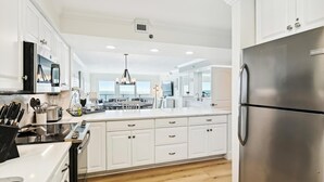 Une cuisine moderne avec des meubles blancs, un réfrigérateur en acier inoxydable et un îlot central doté de sièges.