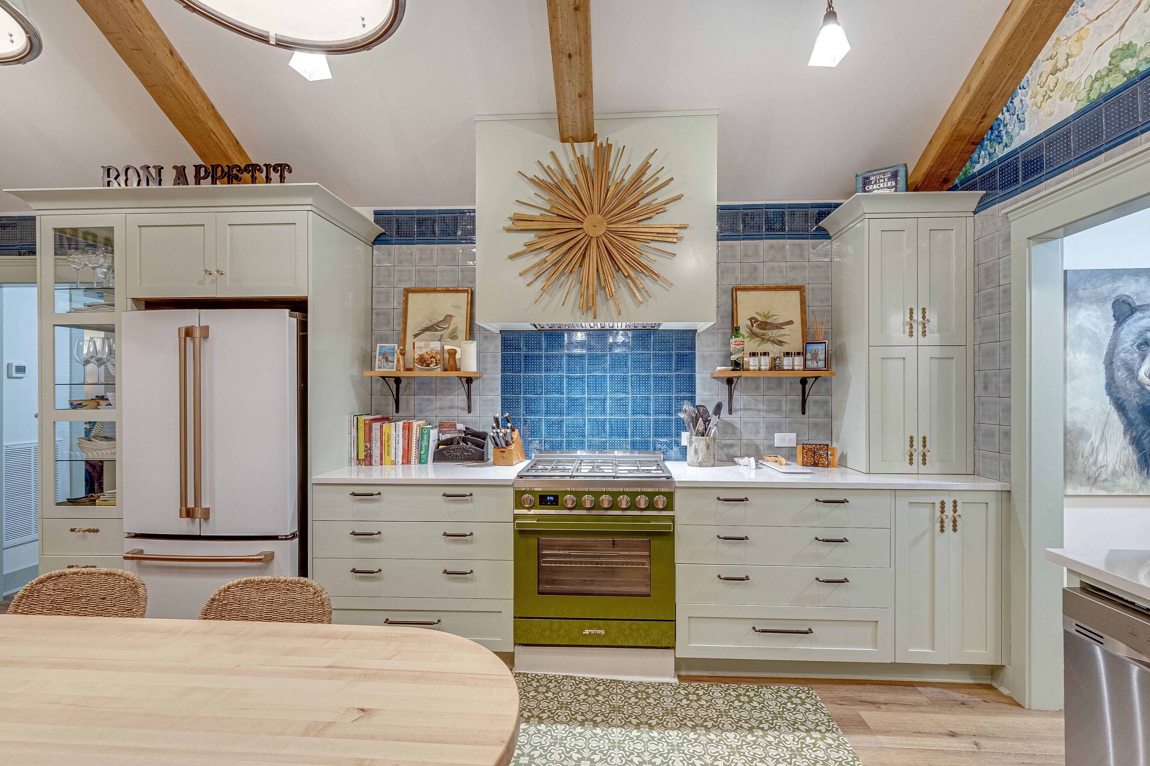 Une cuisine moderne avec des meubles blancs, un poêle vert et un luminaire décoratif en forme de soleil.