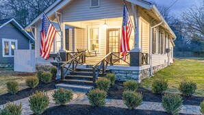 A two-story house with a porch, two American flags, and a stone fireplace. - Completely Renovated Historical Cottage -- Walking distance to Downtown Franklin (Franklin)
