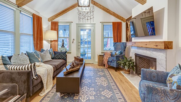 A spacious living room with a high ceiling, wooden beams, a fireplace, and a large window with blinds. - Completely Renovated Historical Cottage -- Walking distance to Downtown Franklin (Franklin)
