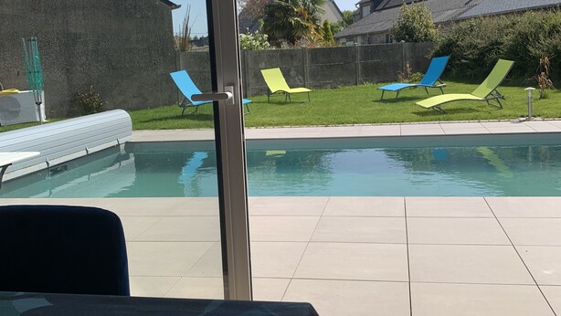 Ein Poolbereich mit freiem Blick auf den Pool, Liegestühlen und einem Gebäude im Hintergrund.