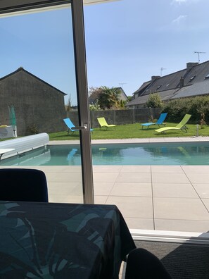 Un espace piscine offrant une vue dégagée sur la piscine, des chaises longues et un bâtiment en arrière-plan.