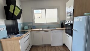 Eine moderne Küche mit weißen Schränken, einem Backofen, einem Geschirrspüler und einem Fenster über der Spüle.