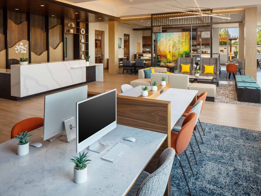 A modern office space with a reception desk, computer workstations, and a dining area with a large painting.