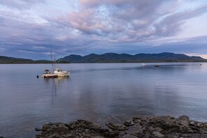 A calm lake with a small boat docked on the shore, surrounded by rocky terrain and distant mountains. - Salmon Run Vacation Rental! (Ketchikan)