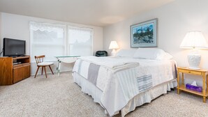 Ein Schlafzimmer mit Bett, Schreibtisch, Stuhl, Fernseher und Lampe.