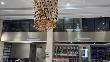A spacious lobby with a large decorative hanging light fixture, a reception desk, and a seating area.