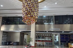 Eine geräumige Lobby mit einer großen, dekorativen Hängeleuchte, einem Empfangstresen und einer Sitzgelegenheit.