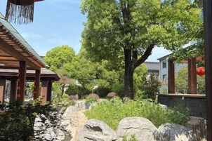 Un edificio tradicional japonés con estructura de madera y un sendero de piedra que conduce a un gran árbol.