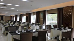 A hotel dining area with multiple tables and chairs, arranged in rows. - Fenghua Lizhi Hotel (Siyang)