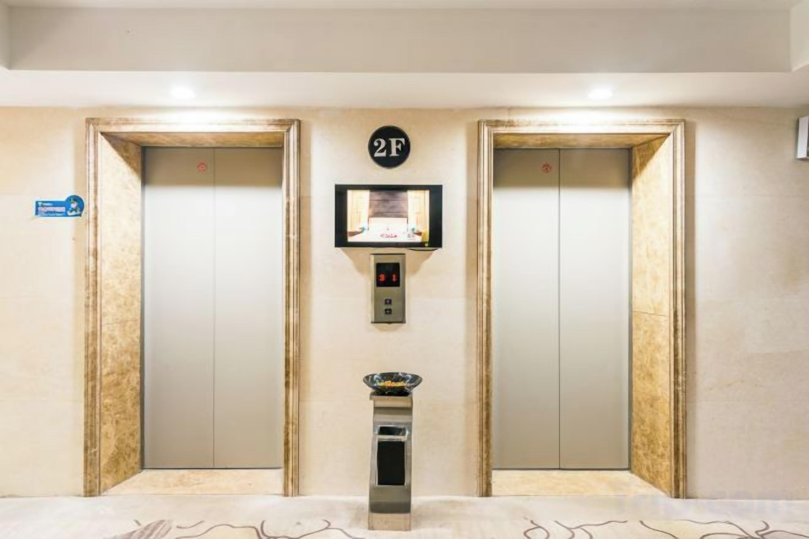 An elevator with a digital display and a button panel, flanked by two doors with a sign indicating the floor.