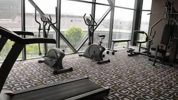 A gym with a treadmill, elliptical, and weight machines, large windows, and a patterned floor.