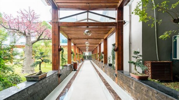 A covered walkway with stone walls and potted plants. - Fenghua Lizhi Hotel (Siyang)