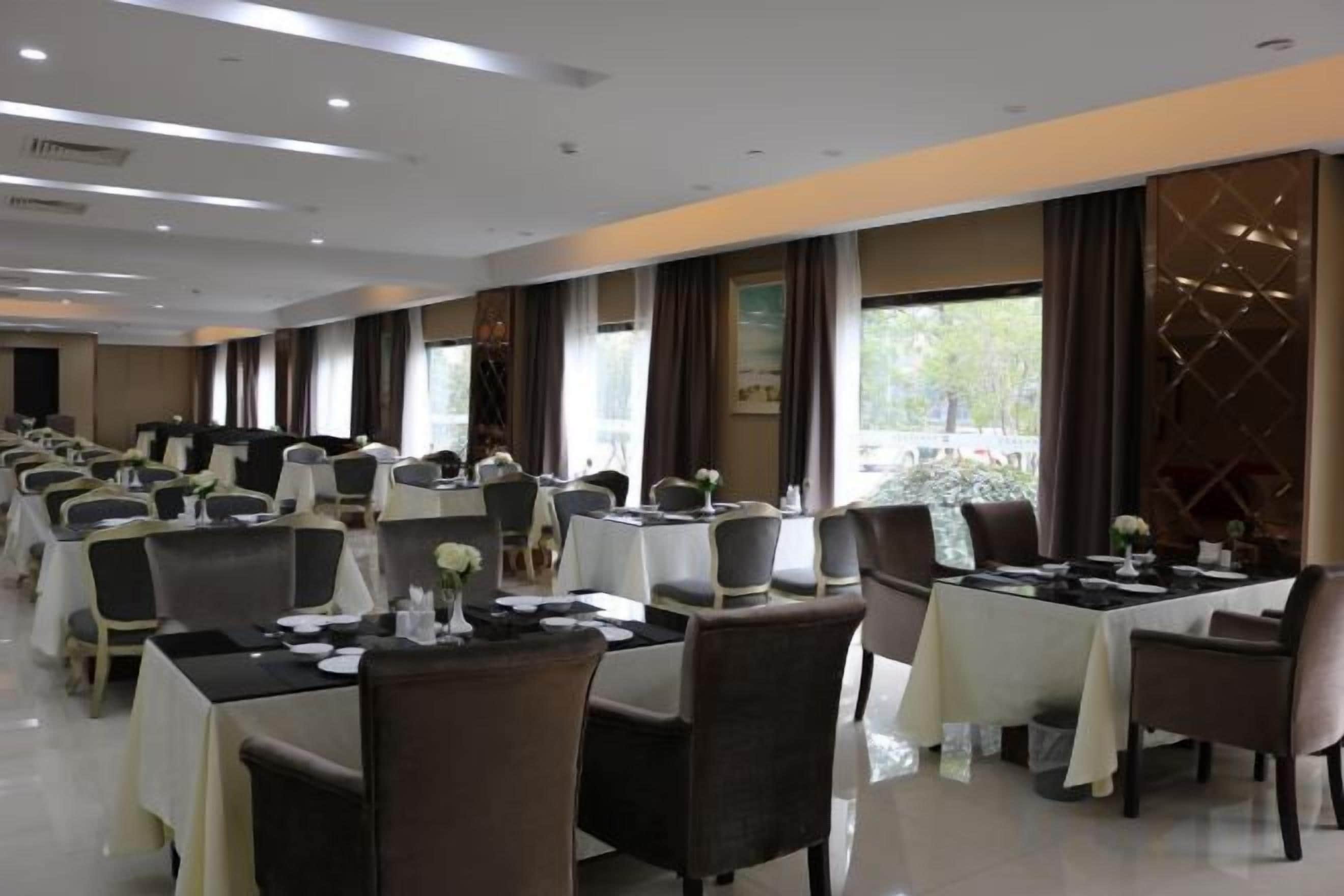 A conference room with multiple tables and chairs, large windows, and a view of the outdoors.