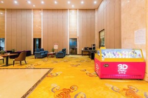 Un vestíbulo con una impresora 3D, sofás, un mostrador de recepción y una alfombra estampada.