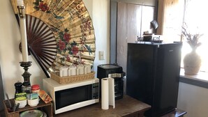 A kitchen counter with a microwave, coffee maker, and a decorative fan.