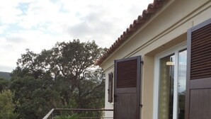 A balcony with two lounge chairs, a potted plant, and a view of trees and hills. - Apartment in residence with swimming pool, janitor, 7 minutes walk from the beach (Zonza)