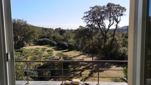 A view from a balcony with a metal railing, overlooking a landscaped garden with various trees and shrubs. - Apartment in residence with swimming pool, janitor, 7 minutes walk from the beach (Zonza)