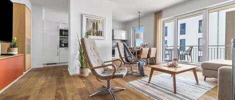 Una sala de estar moderna con suelo de madera, dos sillones, una mesa de centro y un televisor.