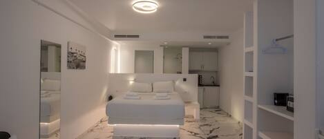 A modern bedroom with a large bed, a walk-in closet, and a bathroom with a shower.
