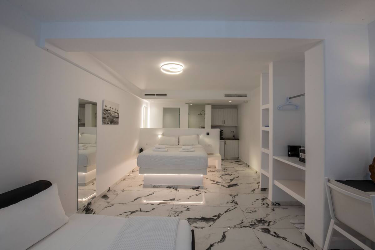 A modern bedroom with a bed, bedside tables, and a bathroom with a shower and sink.