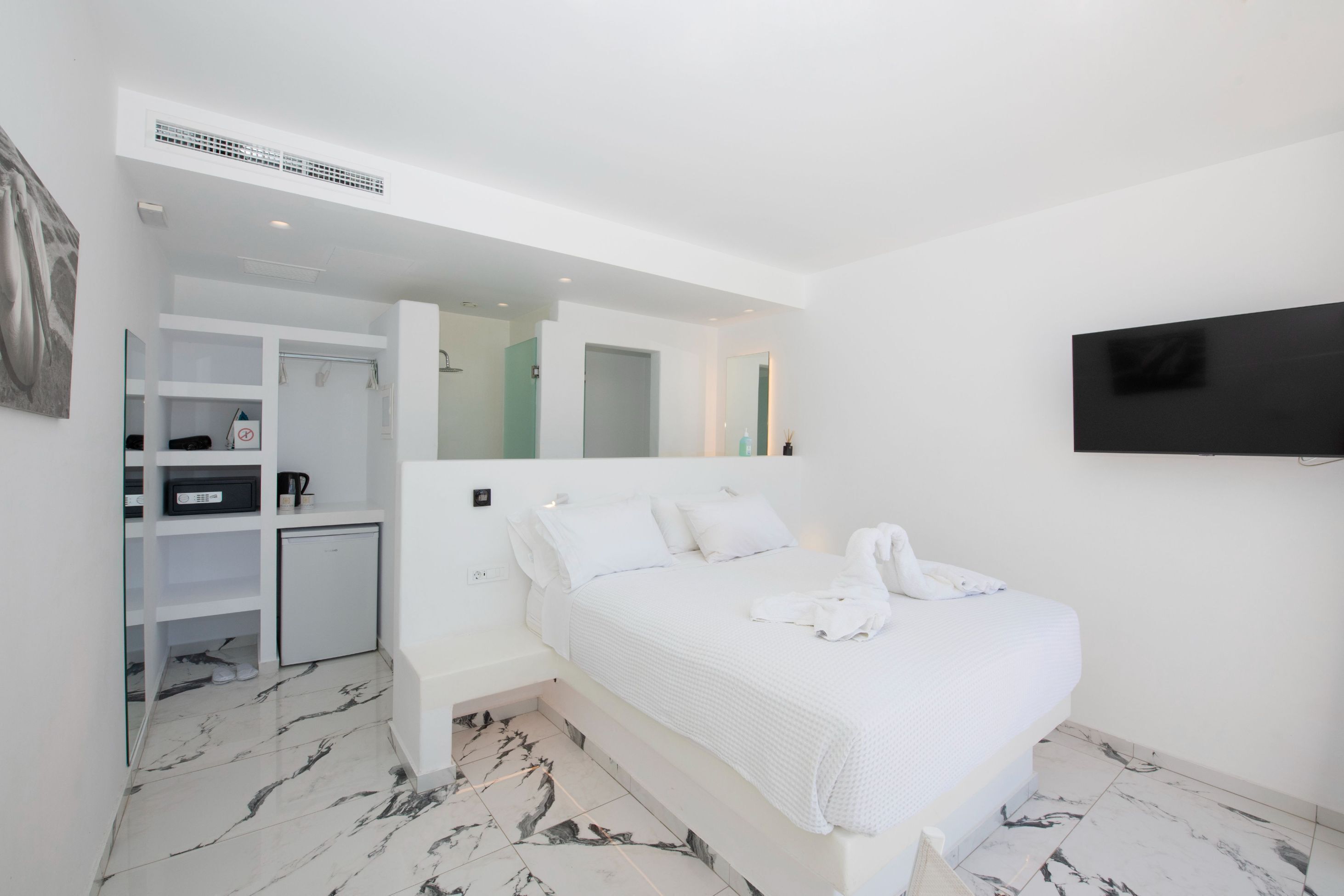 Una camera da letto moderna con un letto, una TV, un armadio e una scrivania.