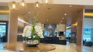 A reception area with a round table, a vase of white flowers, and a reception desk in the background. - Relax in Style: Your Private Paradise Awaits at Dtravellers Home at Shore MOA (Pasay)