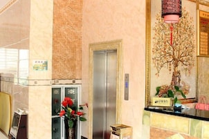 Un vestíbulo con mostrador de recepción, ascensor y una escultura de árbol decorativa.