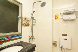 Baño con lavamanos, espejo, ducha y toallero.