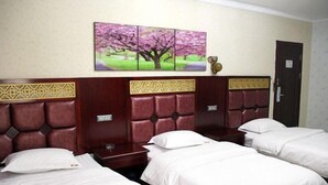 A hotel room with three single beds, a headboard with a decorative panel, a wall-mounted artwork of a tree, and a door with a sign. - Xiangbali Express Hotel Guilin (Lingchuan)