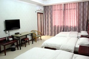 Una habitación de hotel con cama, escritorio con silla, televisor y ventana con cortinas.