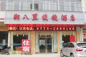 Un hotel con un letrero rojo y blanco, un número de teléfono visible y un cartel que indica habitaciones para alquiler.