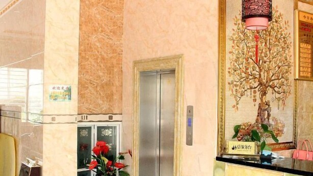 A hotel lobby with a marble floor, an elevator, a reception desk, and a decorative tree mural. - Xiangbali Express Hotel Guilin (Lingchuan)