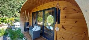 Enjoy a peaceful retreat in this cozy cabin, featuring a patio with a wicker sofa and a garden with a small stream.