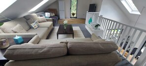 Relax in this inviting space with a comfortable sofa, armchair, and potted plant, offering a clear view of the outdoors.