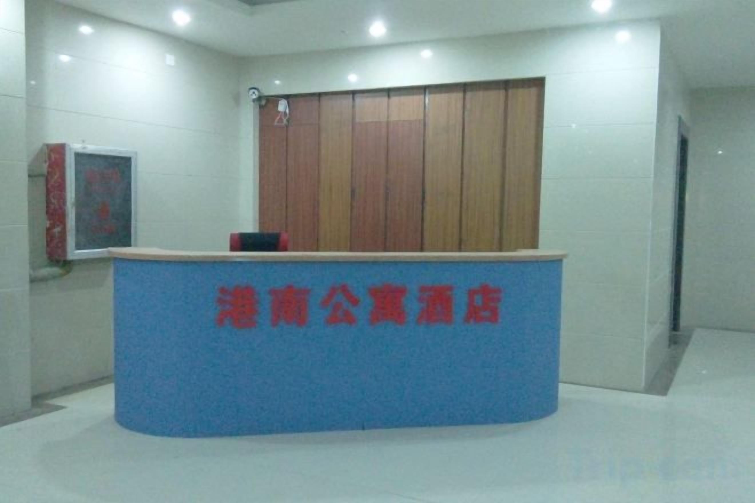 A reception desk with a blue counter and red text, a wooden panel wall, and a framed picture on the wall.