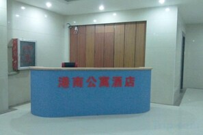 A reception desk with a blue counter and red text, a wooden panel wall, and a framed picture on the wall. - Yuncheng Gangnan Borui Homestay (Yuncheng Yanhu International Airport) (Yuncheng)