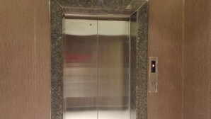 Ascensor con revestimiento metálico y panel de control en el lado derecho.