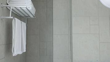 A bathroom with a towel rack holding folded towels and a wall-mounted towel warmer.