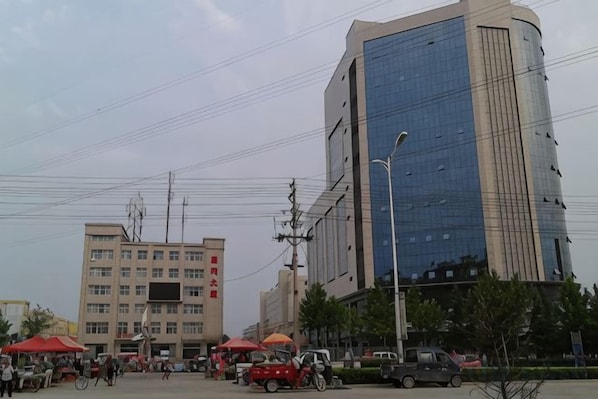 A cityscape with modern buildings, a street with vehicles, and a clear sky. - Yuncheng Gangnan Borui Homestay (Yuncheng Yanhu International Airport) (Yuncheng)
