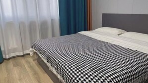 Una habitación de hotel con una cama, cortinas y piso de madera.