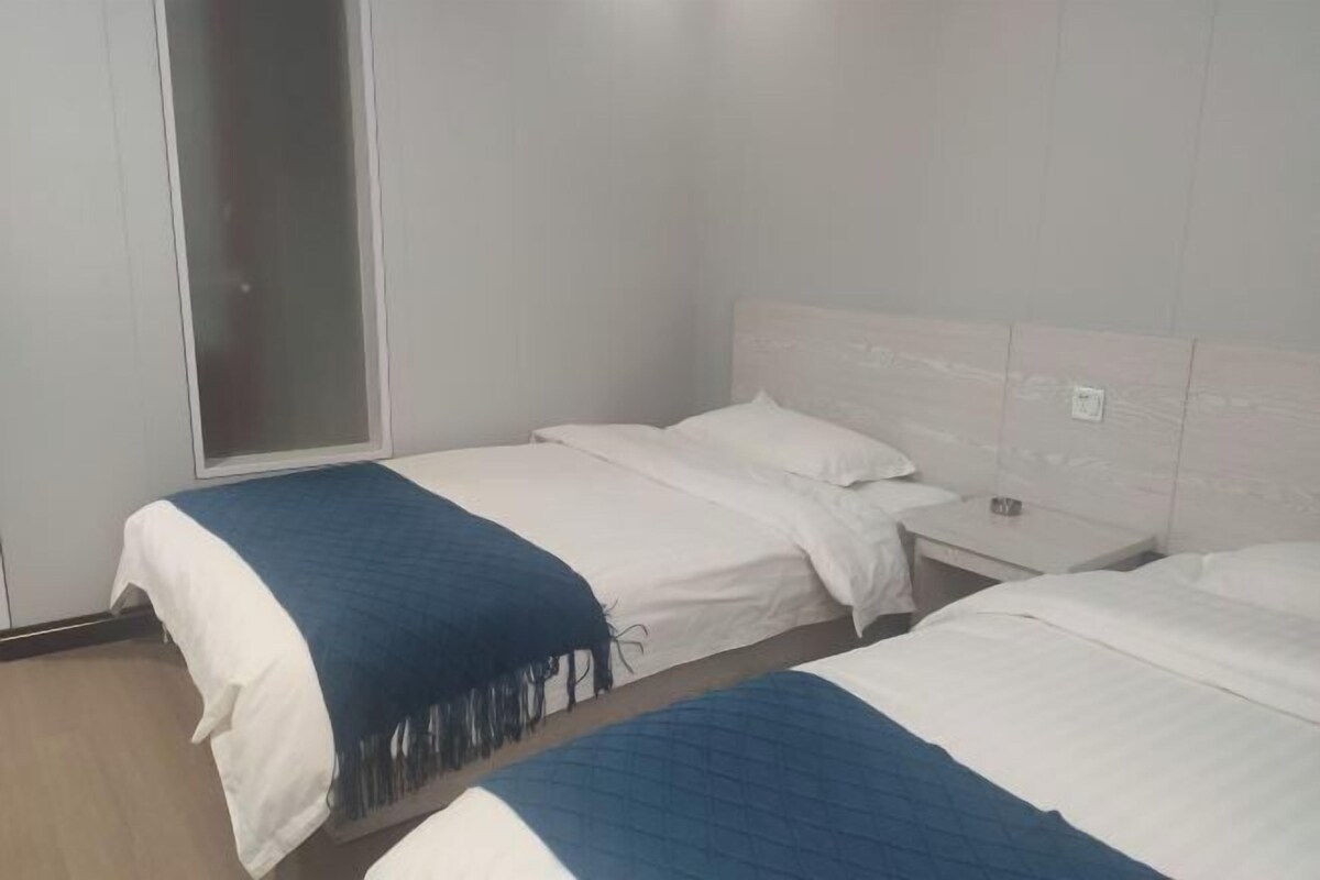 Habitació d'hotel amb dos llits, una tauleta de nit, una finestra i una porta.