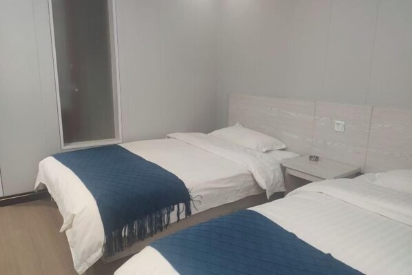 Habitació d'hotel amb dos llits, una tauleta de nit, una finestra i una porta.