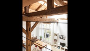 Una habitación con techo de madera, una mesa de comedor con sillas, un televisor y una ventana con cortinas.